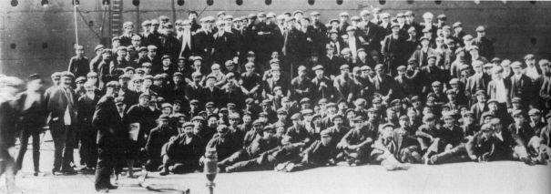 Un gruppo di operai della Harland & Wolff in posa davanti alla murata del TITANIC.